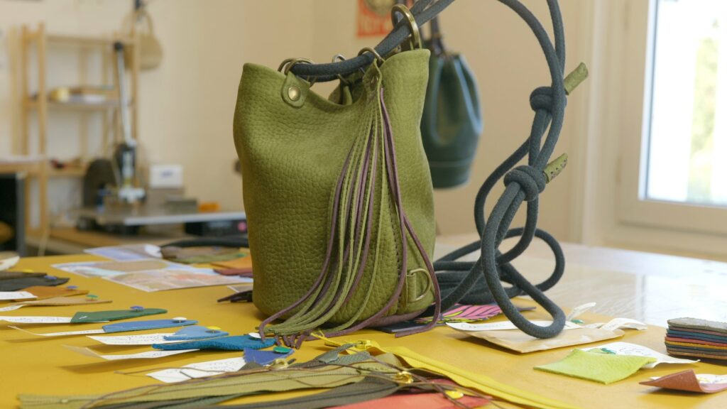 Sac en cuir vert Faméthic posé sur la table de l’atelier